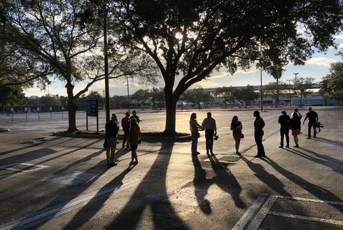 people standing in a parkling lot under a tree