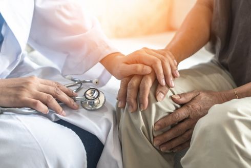 doctor's hand resting on patient's hand to comfort