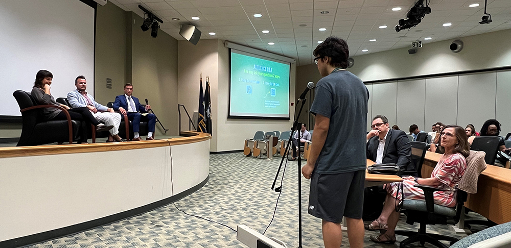 student at a microphone asking the panel a question