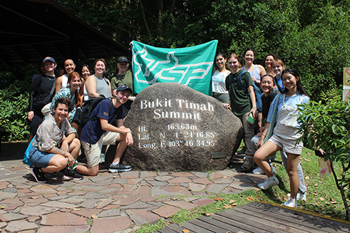 students gathered around large boulder engraved