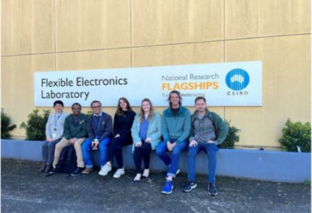USF students and Dr. Sarath Witanachchi sit in front of the flexible electronics laboratory in Australia. (Photo courtesy of Sarath Witanachchi)