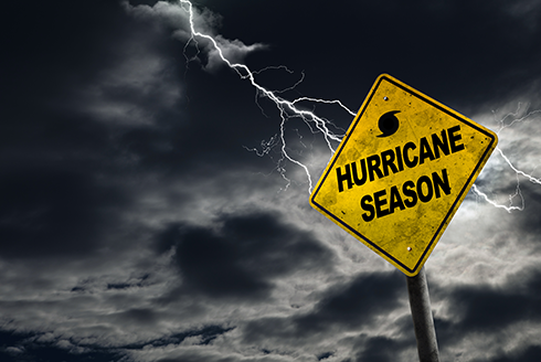 Hurricane Season sign in front of lightning-streaked sky