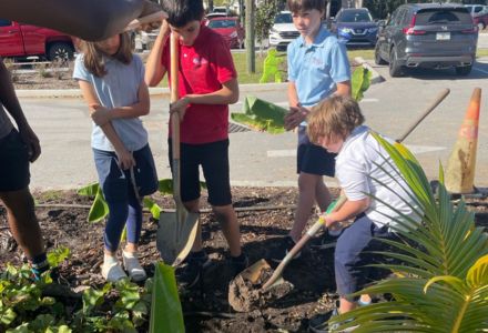 Grades 3-5 students digging a hole to transplant a banana tree. (Photo by Marcela Munoz Marin)