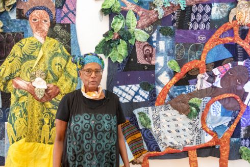 Fiber artist Lauren Austin stands in front of one of her quilts during an art exhibit. (Photo courtesy of Lauren Austin)