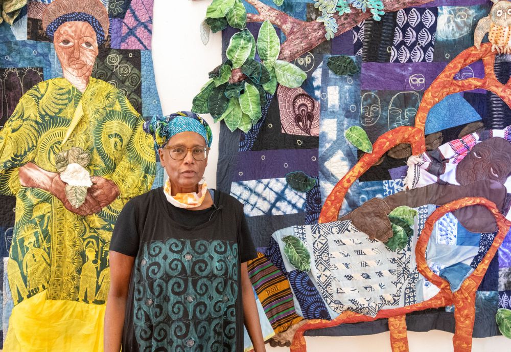 Fiber artist Lauren Austin stands in front of one of her quilts during an art exhibit. (Photo courtesy of Lauren Austin)