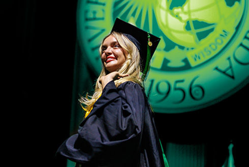 woman wearing cap and gown in front of USF seal