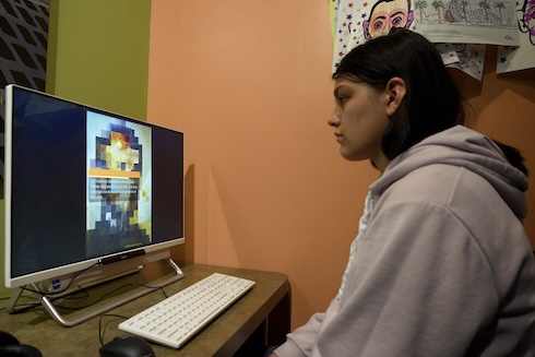 A student views eye-tracking software displaying a pixelated artwork on a computer monitor.