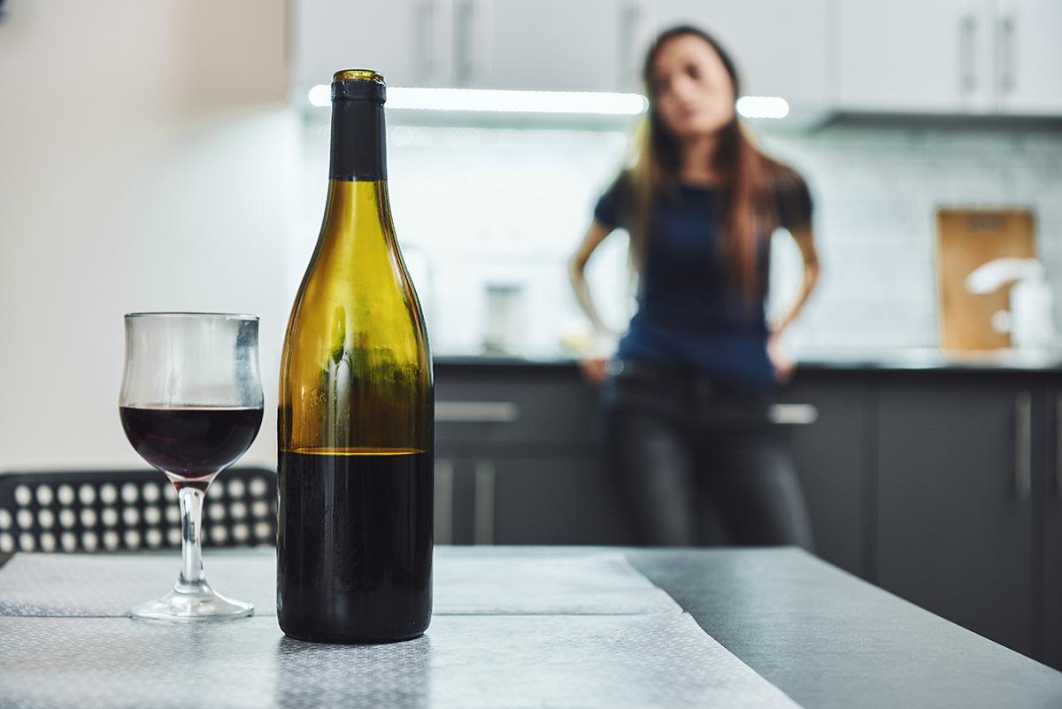 bottle of wine with woman in background