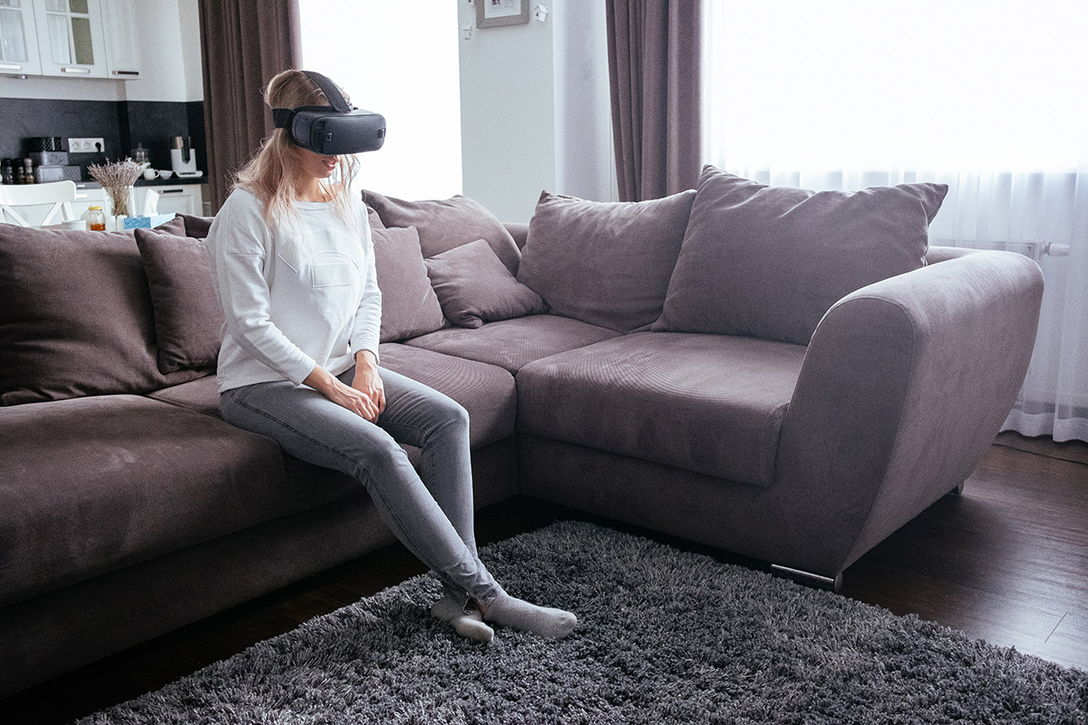 woman sitting on sofa wearing VR mask