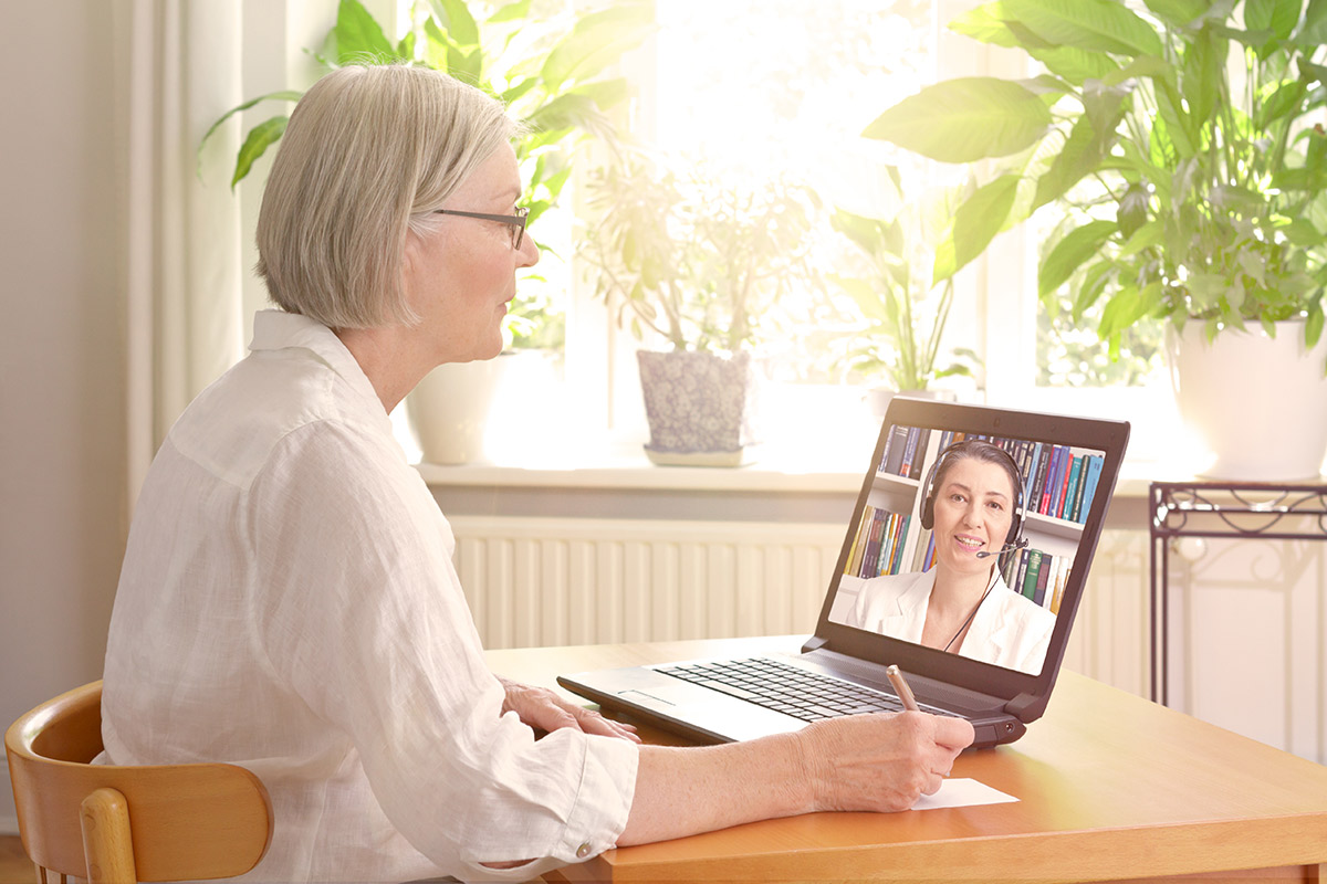 senior woman video conferencing with medical professional on laptop
