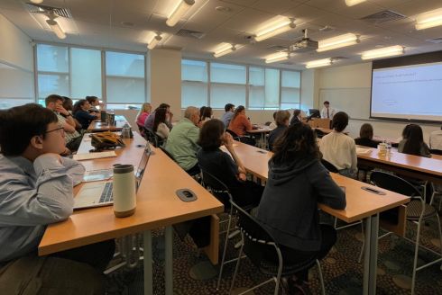 Students seated and watching the presenter at the Conference. Both undergraduate and graduate students may register to present their work during the event. (Photo by Guy Dayhoff)