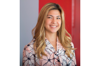 Headshot shows USF English alumna Natalie Kass smiling into the camera in front of a grey and red colorblock background