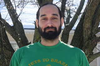 Image shows John A. Nieves smiling at the camera in front of a tree