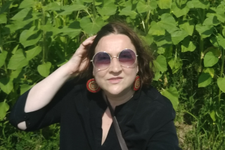 Image shows Anca Garcia standing in front of a wall of leaves