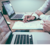two people working on laptops at a desk