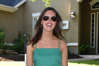 Picture of Nicole Lyssy smiling into the camera, standing in front of a house