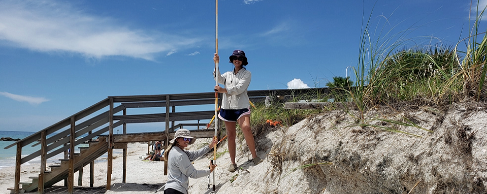 two students taking measurements on the beach