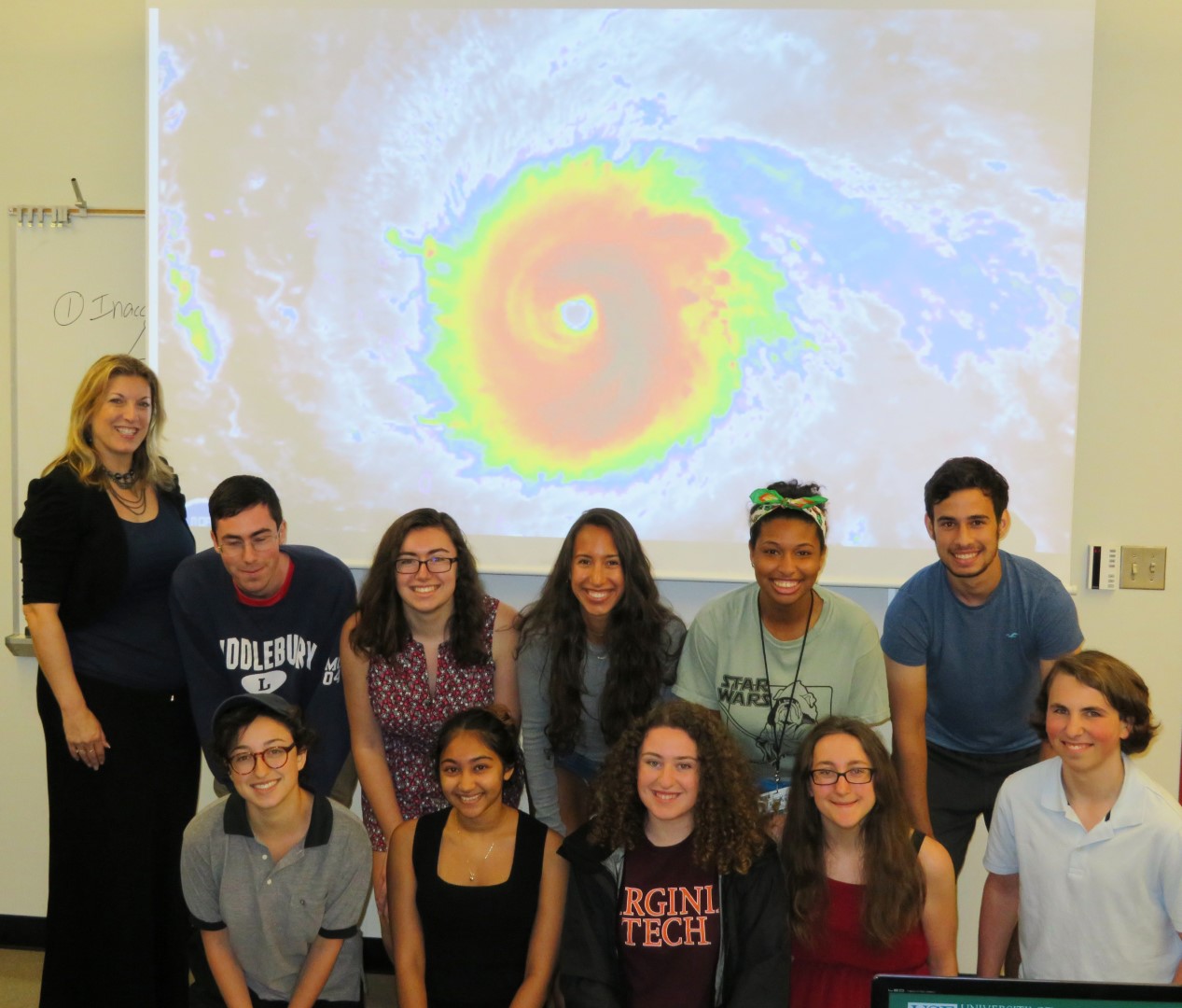 professor collins with group of students in front of a porjector that displays a hurricane