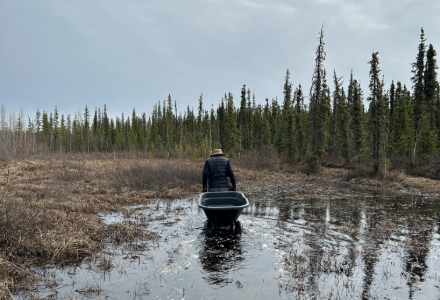 A man can be seen hauling a wheelbarrow.
