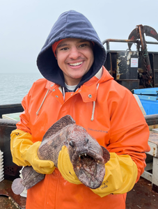 man in water protective gear holding a fish
