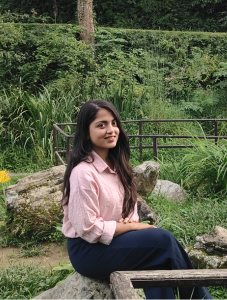 woman with pink shirt sitting on rocks body turned away from camera face facing camera