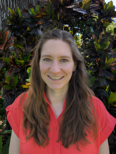 woman smiling vibrant color shirt plants behind her