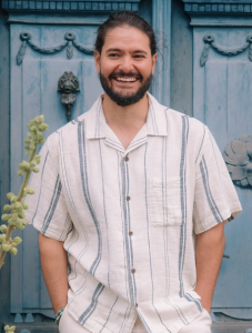 man standing in front of blue doors with hands in pant pockets