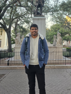 man with hands in pant pockets standing in front of statue