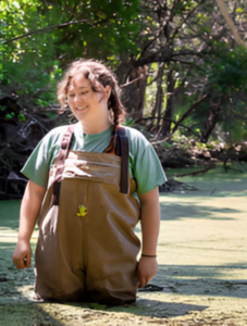 woman standing in boggy water in protective overalls