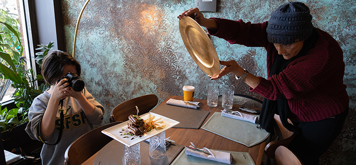 student photographs food plate while instructor assists