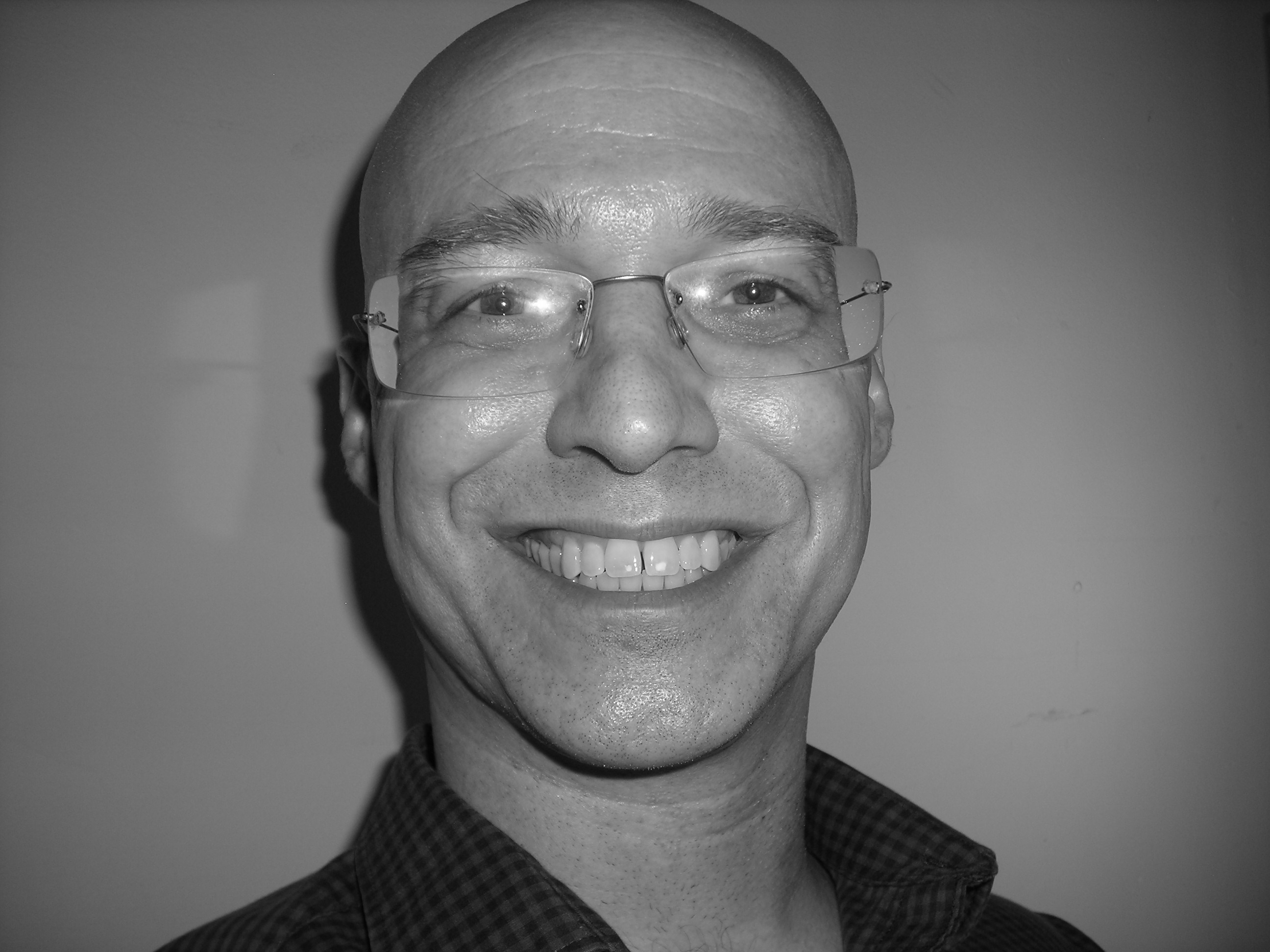 Picture of a man with glasses smiling.