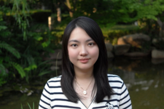 Zhuwen is smiling at the camera with nature in the background