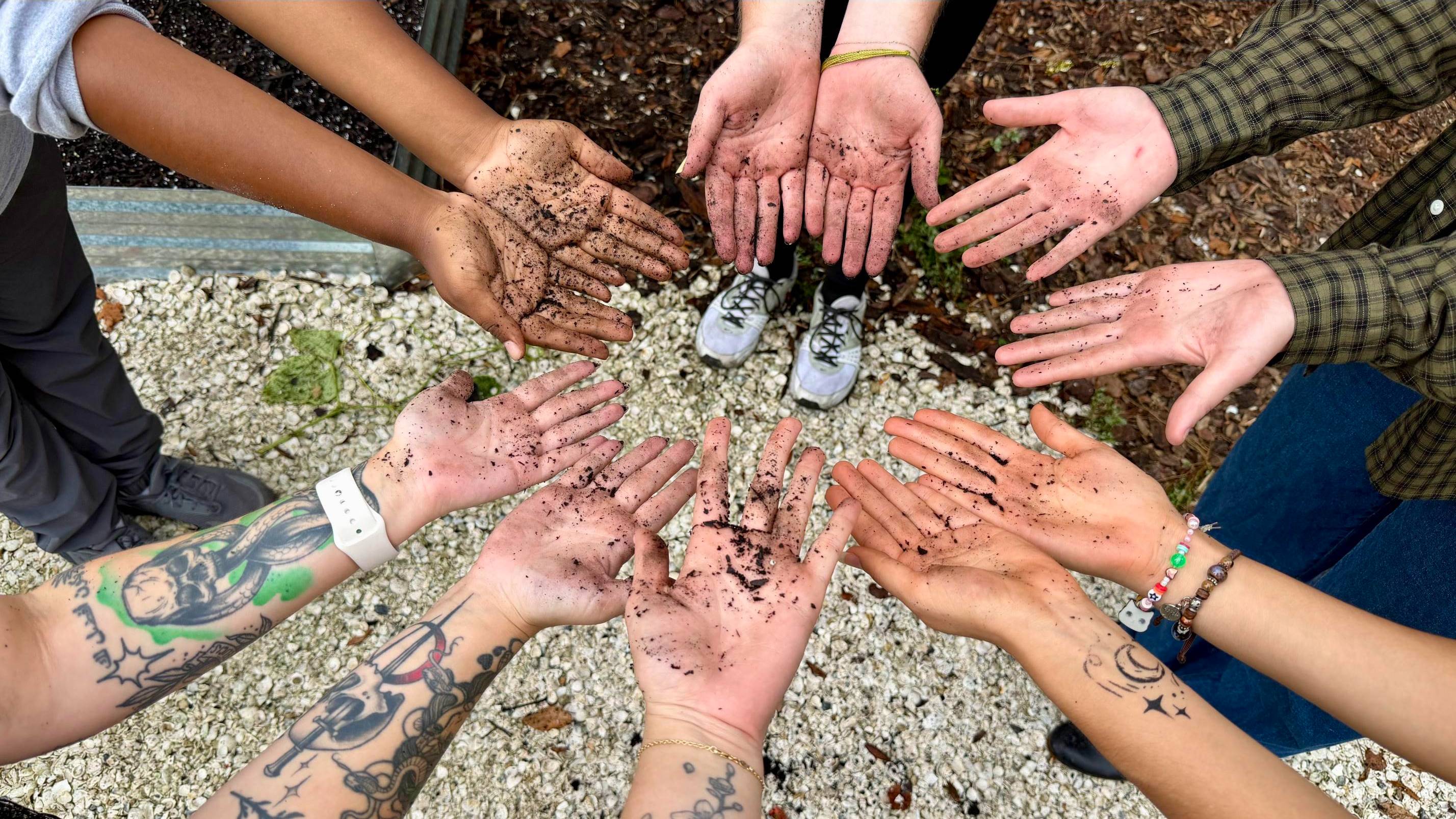 Hands in a circle covered in dirt