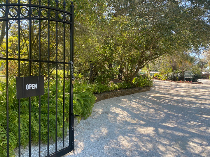 open garden gate with "Open" sign leading to path