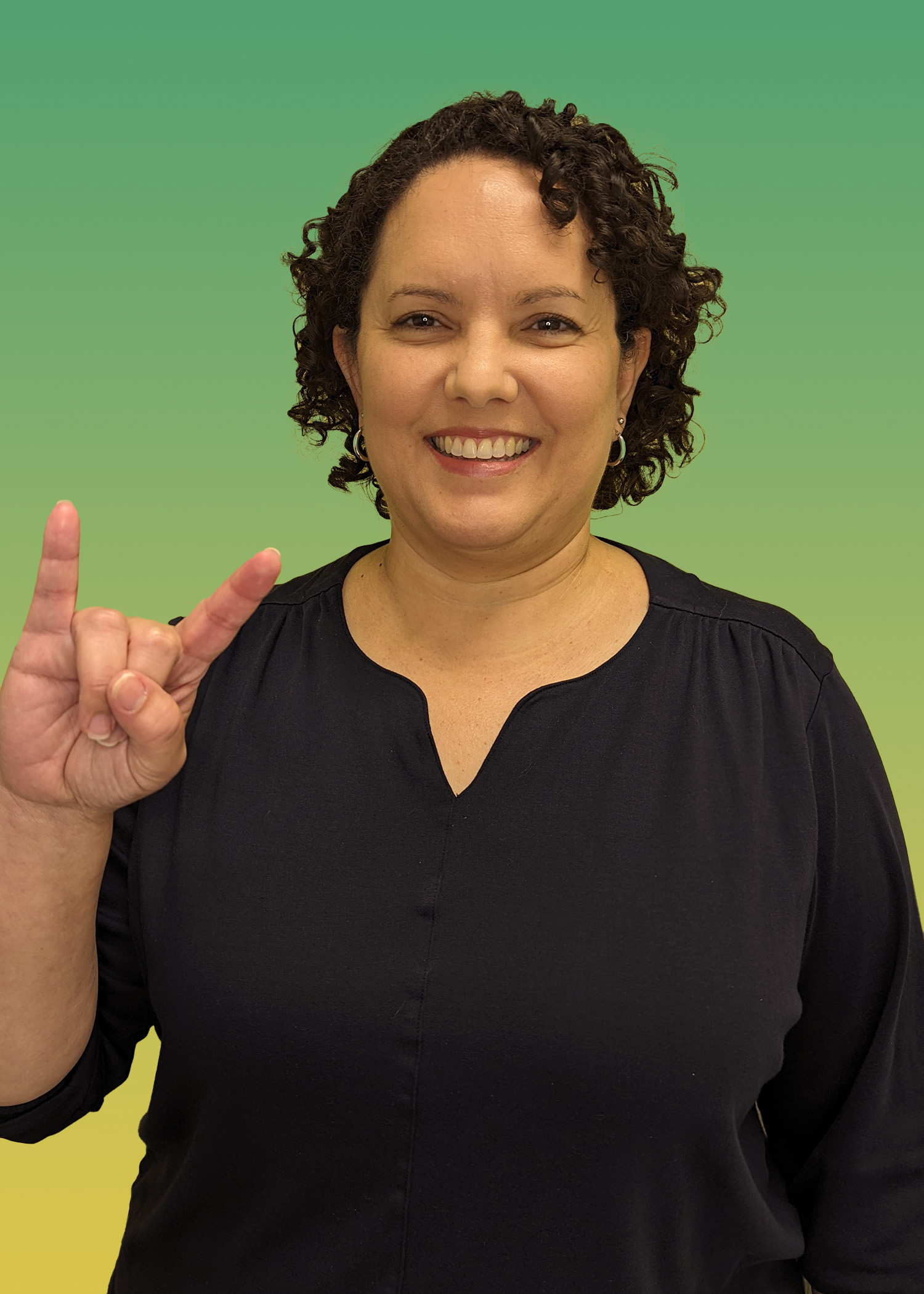 Portrait of Dr. Ana Torres-Ayala in a black blouse and holding up a Go Bulls hand sign. 