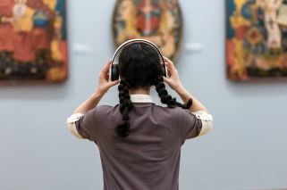 woman with headphones viewing a painting