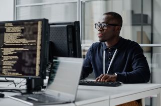 man with glasses seated in computer lab