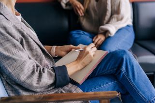 person writing in notebook on their lap
