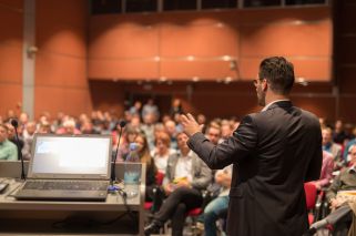 man speaking before large audience