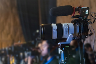 Video camera on tripod beside chairs