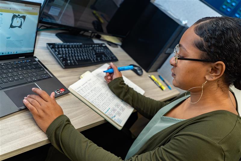 woman sitting at computer with notebook