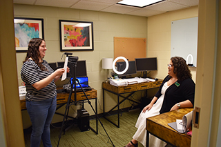 Student intern filming with tripod and light