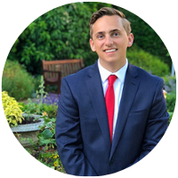 Ryan in the garden wearing a blue suit with a red tie