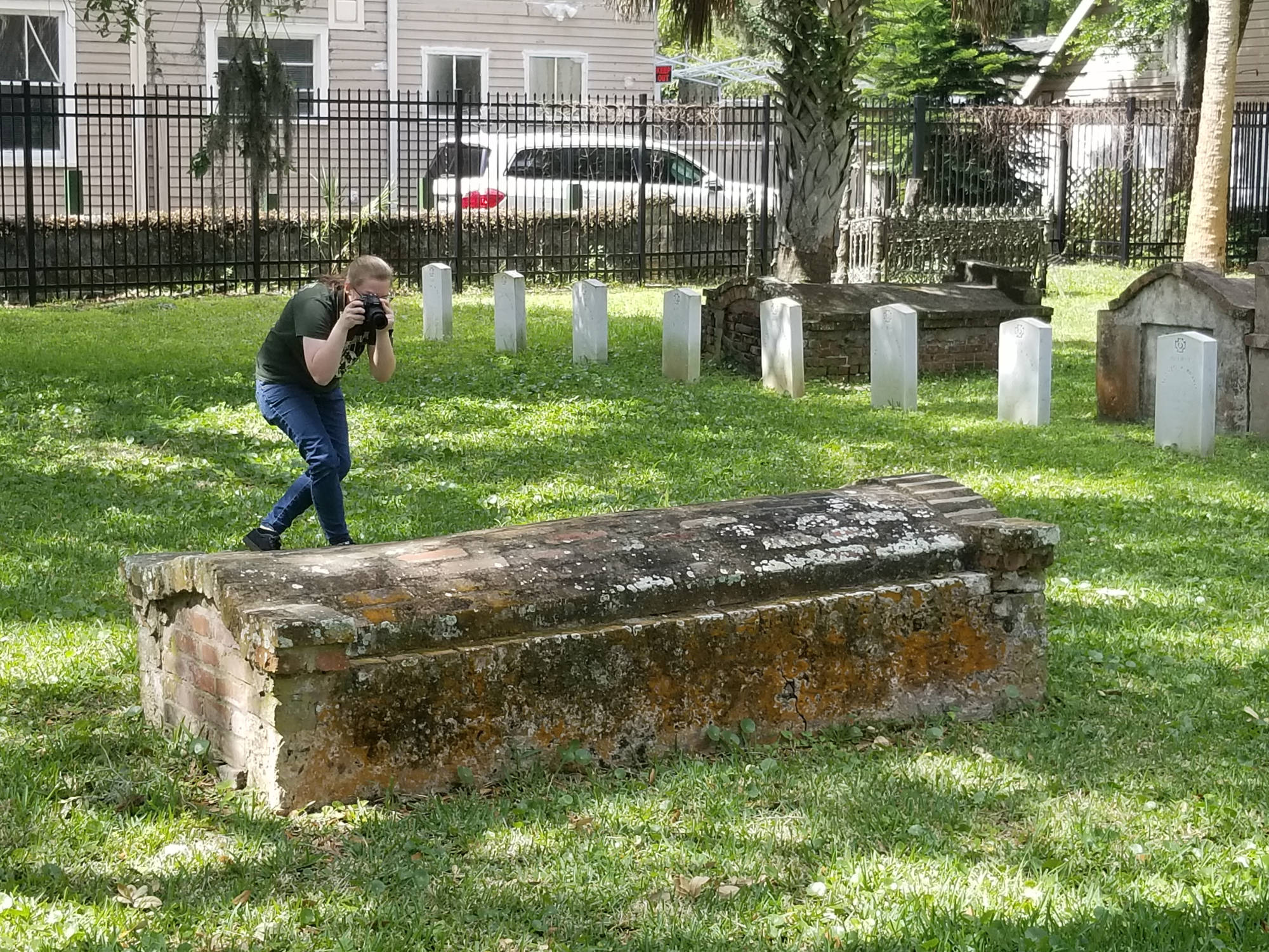 student photographing tomb in cemetery