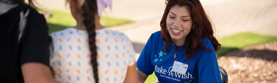 Maria Bustinza working at an event booth from Make A Wish
