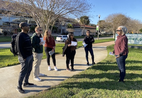 group of people huddled on a path outside of USF sign