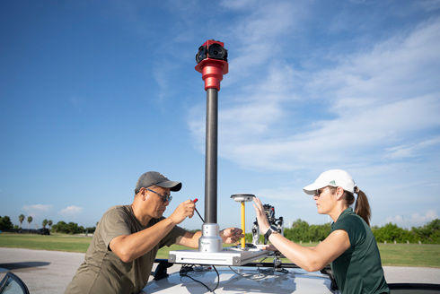 Youjung Kim and Laura Harrison outdoors, setting up 3D scanning equipment for field research. (Photo credit: Corey Lepak)