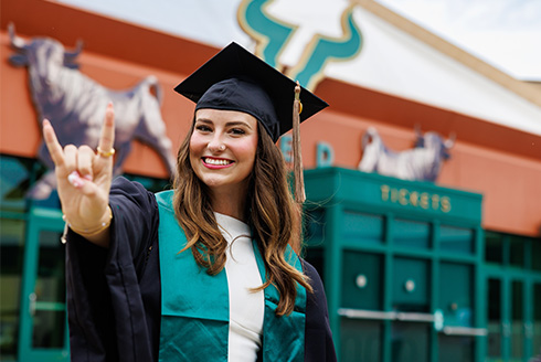 graduate in cap and gown with bull horns hand