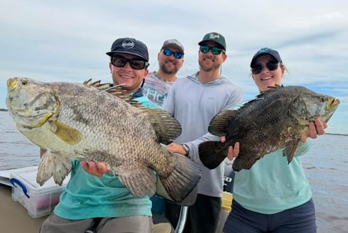 Lucas Griffin and three research partners hold a cobia and tripletail on a boat in the Gulf.