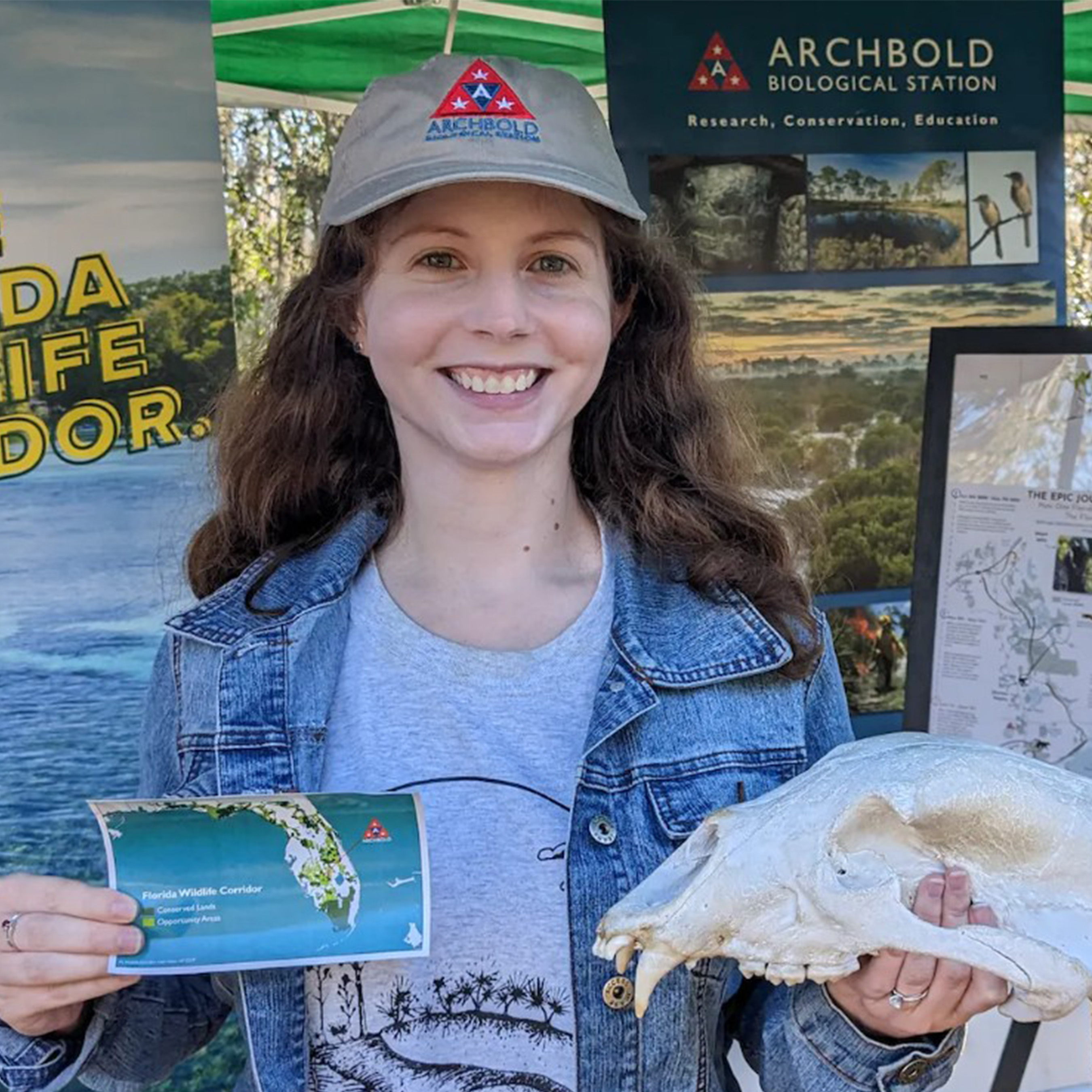 Archbold Biological Station Intern holding an animal skull in a jean jacket and Archbold Hat.